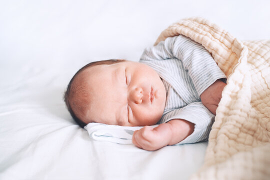 Newborn sleep at first days of life. Portrait of new born baby one week old in crib in cloth background.