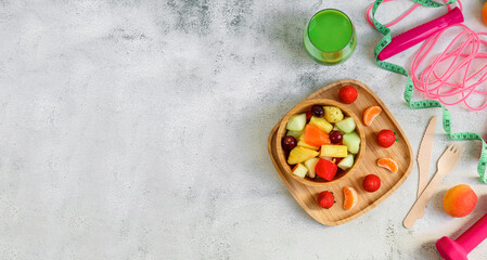 Obraz na płótnie Canvas Fruit salad and fitness accessory on cement background.