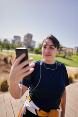  A beautiful white woman with brown hair and a sports outfit sends a message by cell phone to one of her friends