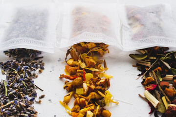 Dry tea in filter teabag sachet on white background. Green leaves, fruits, berries, lavender drink...