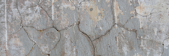 Old wall with cracked plaster. Weathered rough surface. Wide panoramic texture for background and design.