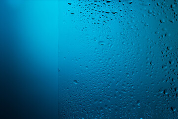 Water drops on glass in blue light.