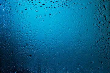 Water drops on glass in blue light.