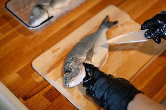 Peraon cooking raw fish in kitchen