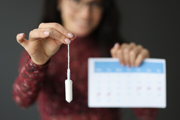 Woman holds gynecological swab and calendar in her hand