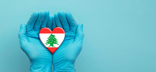 Doctors hands wearing surgical gloves holding Lebanon flag heart