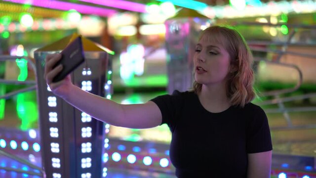 Chica rubia espa&ntilde;ola sonriendo y posando en zona de atracciones de una feria