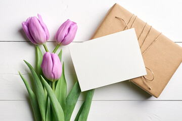 Fototapeta premium Greeting card mockup with gift box and tulip flowers on white wooden background