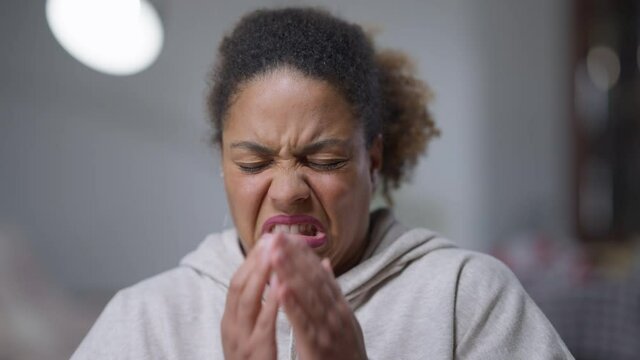 Close-up portrait of African American woman with disgust facial expression closing face with hands. Dissatisfied young beautiful lady hiding from disgusting something. Revulsion concept