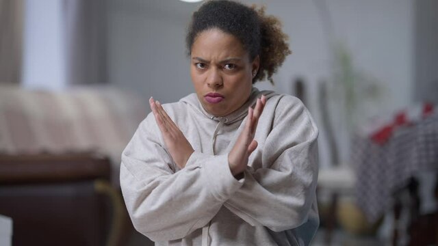Middle shot of shocked African American woman crossing hands rejecting looking at camera. Portrait of young dazed lady posing denying refusing. Emotions concept
