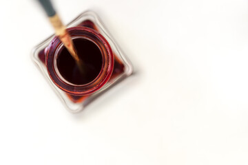 isolated deep red inkwell bottle - viewed from above with scripting paint brush - on white