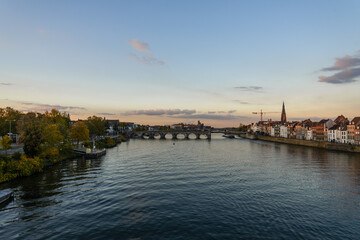 Fototapeta premium Outdoor sunny view of Meuse river , Sint Servaasbrug, historical footbridge, and cityscape from Hoge Brug in Maastricht, Netherlands during sunset time and dramatic twilight sky. 