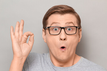 Portrait of amazed impressed blond mature man showing okay gesture
