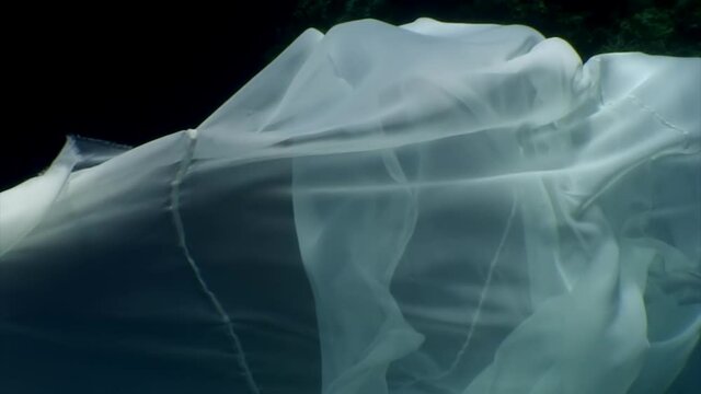 Young woman underwater model in white cloth on background of blue water. Concept of creativity and art of creating images.