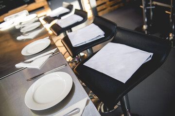 Table setting with leather bar chairs, white napkins, white plates and silverware 