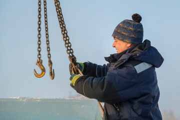 Fitter in a blue jacket works with a chain metal sling
