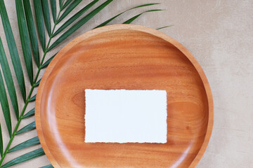Summer wedding stationery mock-up scene. Blank business card, invitation in sunlight. Wooden plate, palm leaves, greeting card. Concrete texture background. Flat lay, top view.