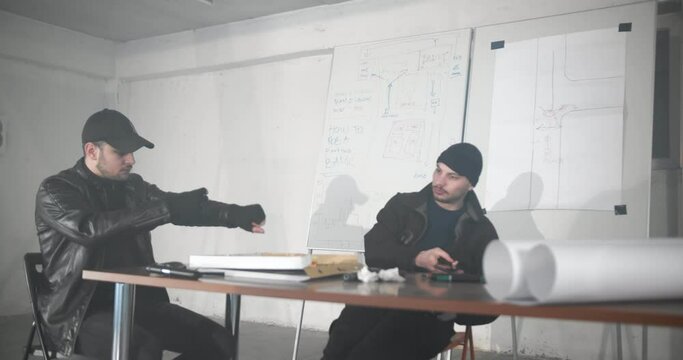 Criminals planning a heist in the garage, drawing on a map