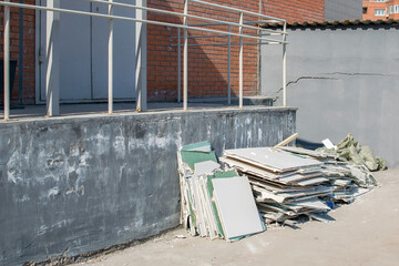a pile of construction debris, broken drywall, lies near a brick building in a new area of residential buildings under construction