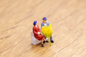 黄色い菜の花一輪とベンチに座るカップル