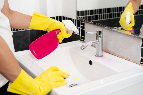 Hand Cleaning Bathroom Sink With Spray And Sponge