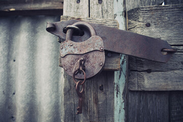 Iron rusty lock with a key. Closed door.