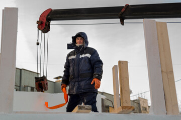 A portrait of a fitter in a blue jacket at the hook of a truck crane