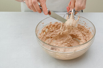 The chocolate cake frosting  for Chocolate Cake close up in a bowl. Beating cream using an electric hand mixer