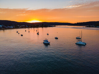 Aerial sunrise waterscape over the channel with orange clouds and boats below