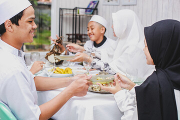 Fototapeta na wymiar Happy asian family muslim eating together during eid mubarak celebration 