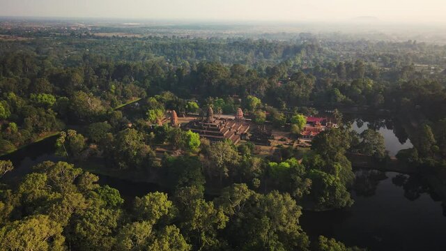 Angkorian temple, Bakong, nested in the mystic Cambodian jungle and early morning mist, aerial drone footage