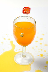 Splash of orange liquid in a glass from a thrown dice