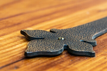 A close-up of a vintage antique iron hinge with a modern screw