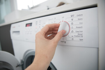 Caucasian female hand turning knob button washing machine white laundry chores domestic cleaning