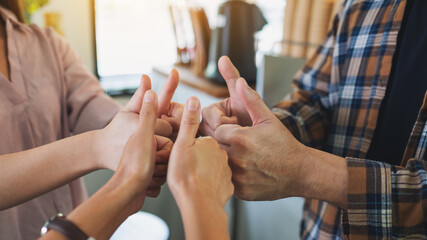 A group of people making thumb up hands sign in circle