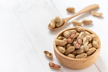 Peanuts in a wooden bowl on white background,