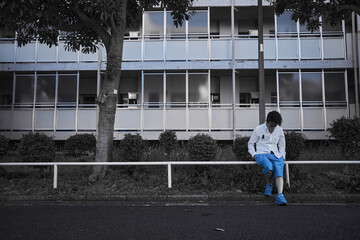 団地の通りで腰掛ける白いシャツの男性