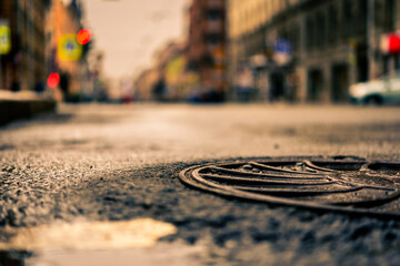 Fototapeta na wymiar Rainy day in the big city, the empty road. Close up view of a hatch at the level of the asphalt
