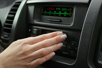 Woman tuning into a radio station in car