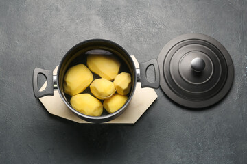 Cooking pot with peeled potatoes on dark background