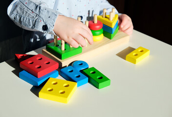 Wooden multi-colored children's pyramid for mental development in children's hands.