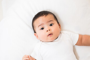 A cute baby wearing a white dress Stay with parents in the house