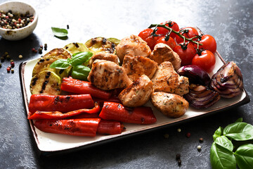 Grilled meat and vegetables set: tomatoes, onions, zucchini, peppers in a plate on a concrete background. Picnic. BBQ menu.