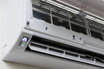The air conditioner is hung on the wall of the house. Open the front cover to wait for maintenance.