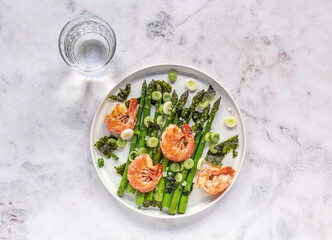 Healthy appetizer. Seasonal salad from shrimp prawns and green asparagus. Served with green onion and dried seaweed nori in plate. 