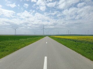Fototapeta na wymiar Road towards blues sky with wind turbine