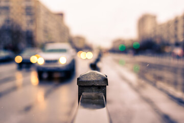 Rainy day in the big city, the headlights of the approaching cars. Close up view, from the handrail on the sidewalk level