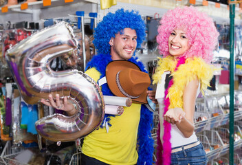 Couple is having fun in colorful clown wigs in the shop.