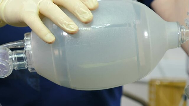 Anesthesiologist with resuscitation breathing bag or Ambu bag in hands. Life saving concept. rescue patients in emergency. Mask for artificial lungs ventilation. Breathing bag with valve inflates and