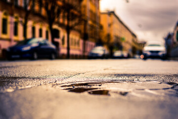 Rainy day in the big city, the street with parked cars. Close up view of a hatch at the level of the asphalt